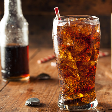 A cola beverage in a glass with a straw.